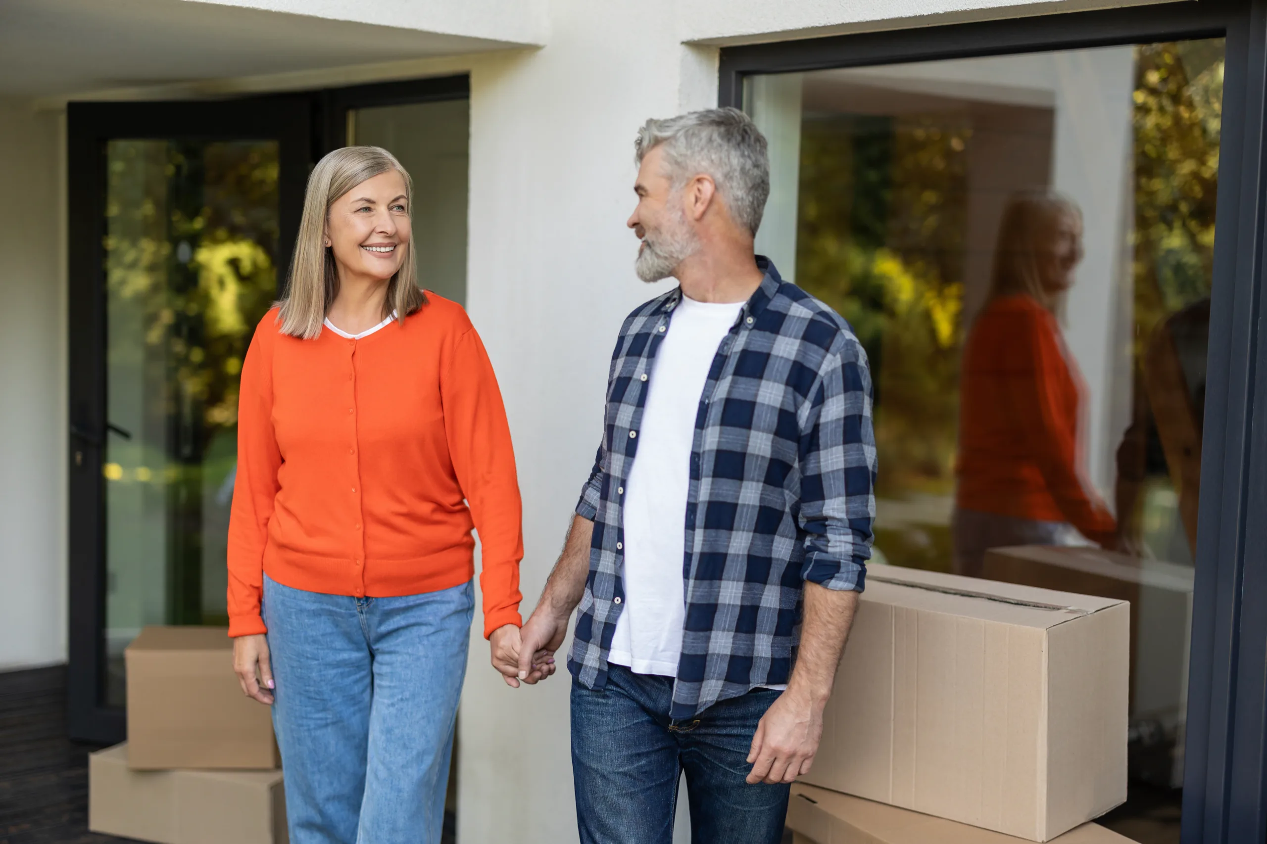 Couple holding hands in their doorway with moving boxes behind them
