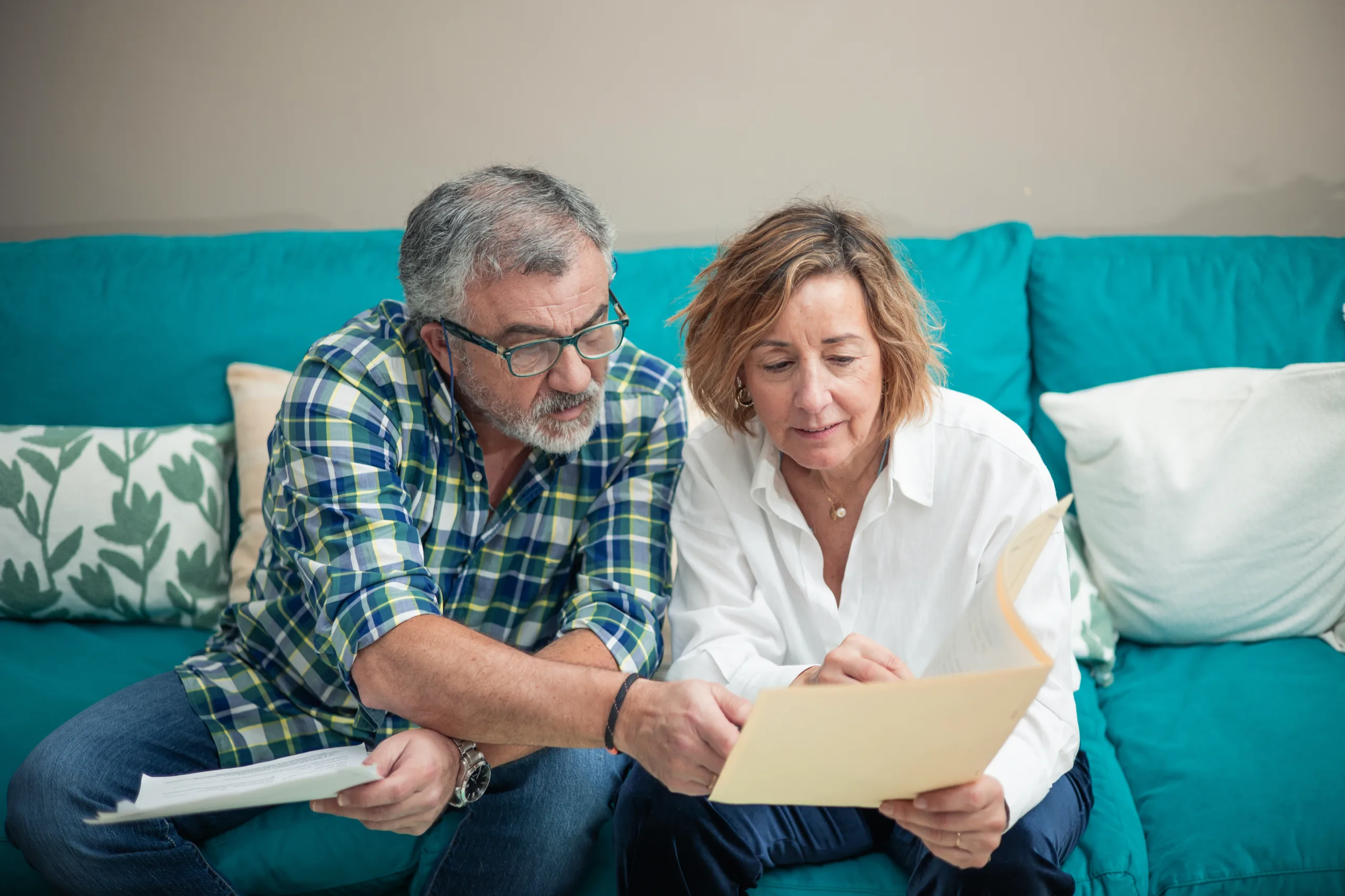 Couple on their couch looking over a letter together