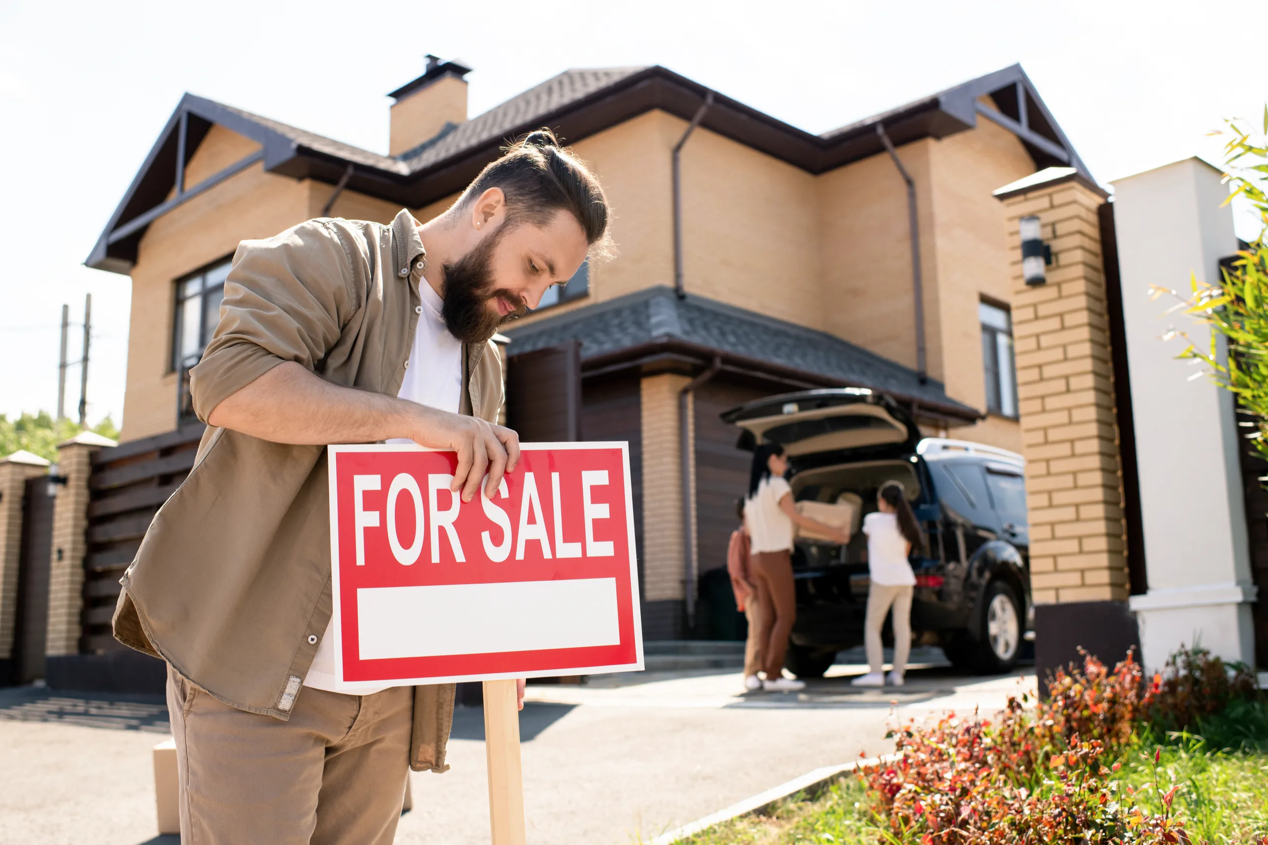 Homeowner putting a for sale sign in his front yard