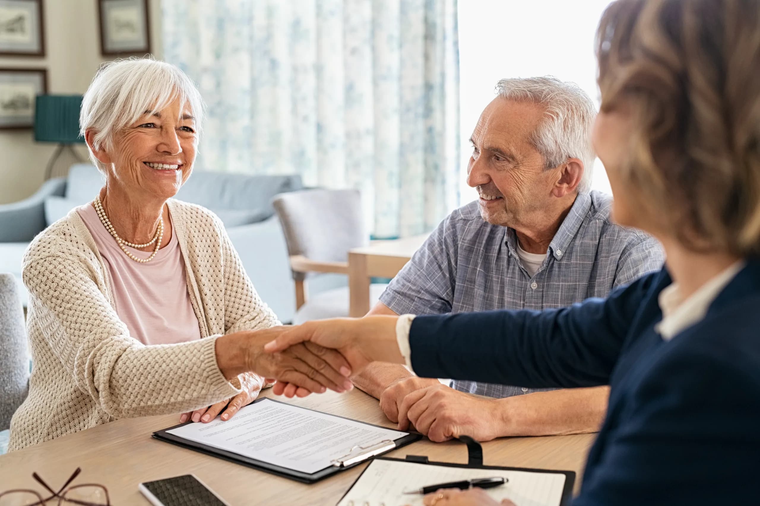 Older couple shaking hands with a real estate agent at a table
